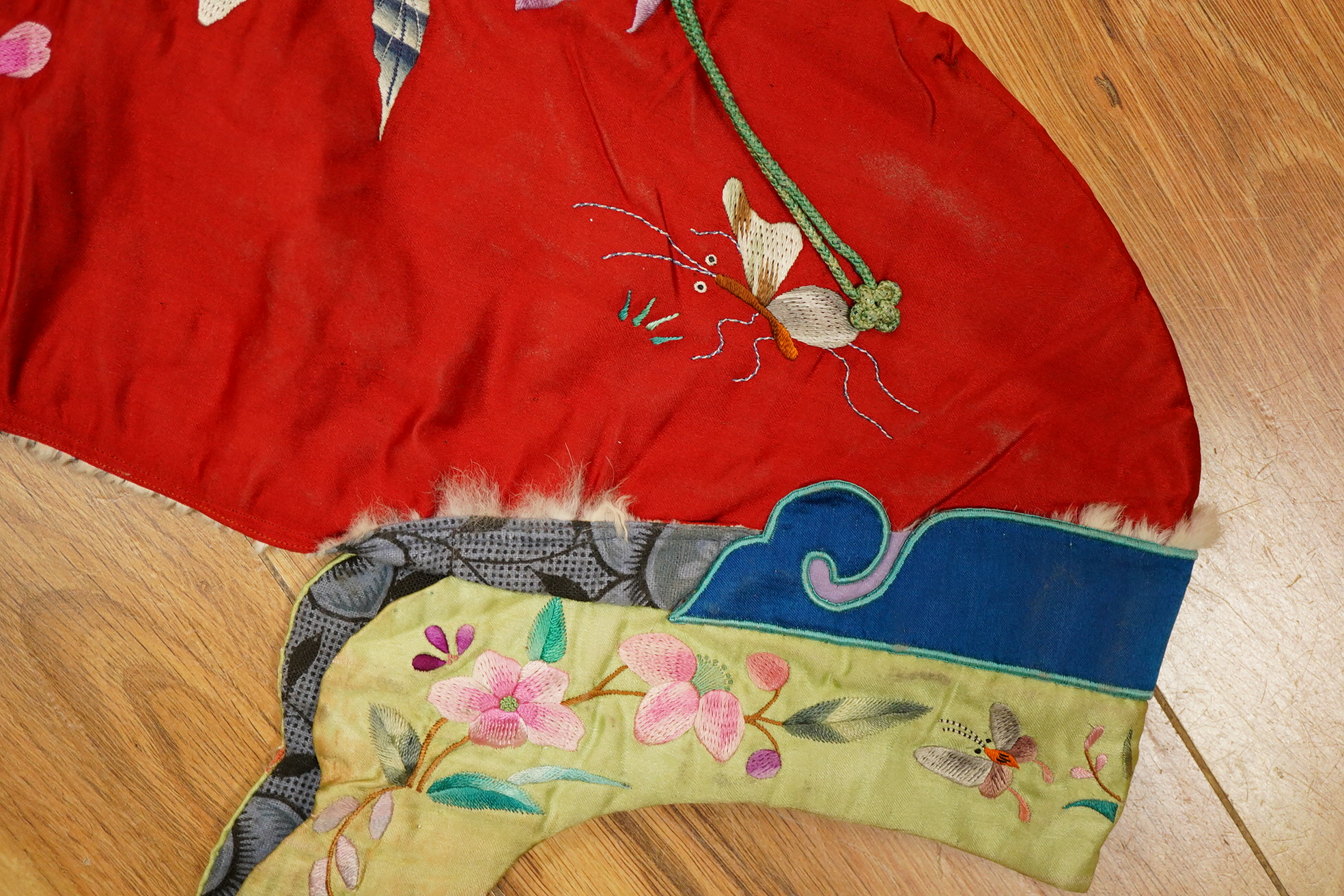A 20th century possibly Miao, child’s multi coloured silk embroidered and padded winter hood, with fur trim and ornate tasselled decoration, 54cm long. Condition - the light green silk edge has worn and has lightly disco